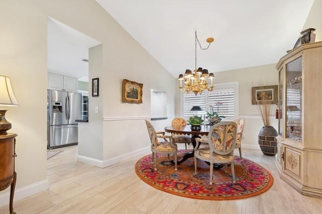 dining area with an inviting chandelier, lofted ceiling, and light hardwood / wood-style floors