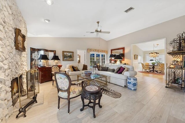 living room featuring plenty of natural light, lofted ceiling, a fireplace, and light hardwood / wood-style flooring