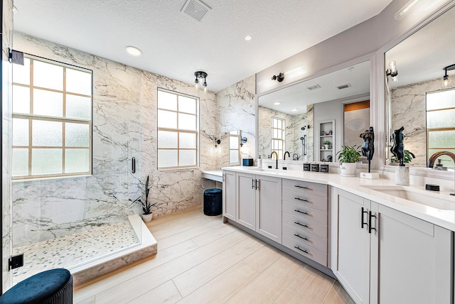 bathroom with visible vents, a sink, a marble finish shower, and wood finished floors