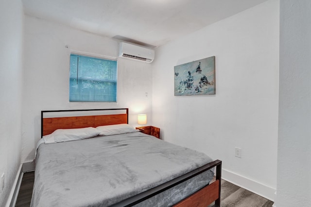 bedroom with a wall unit AC and dark hardwood / wood-style floors