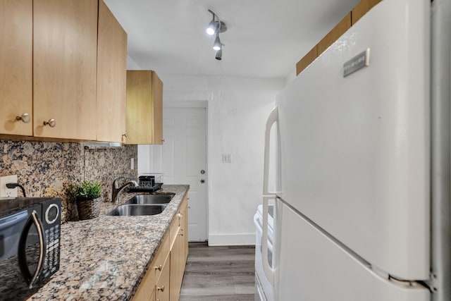 kitchen with sink, decorative backsplash, white refrigerator, hardwood / wood-style flooring, and light stone counters