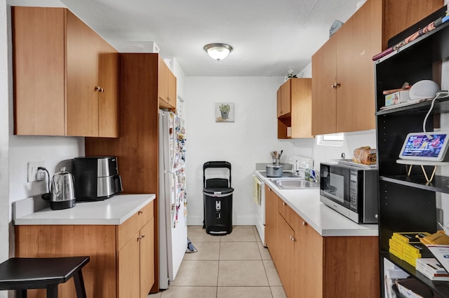 kitchen featuring white refrigerator, sink, a breakfast bar area, and light tile patterned floors