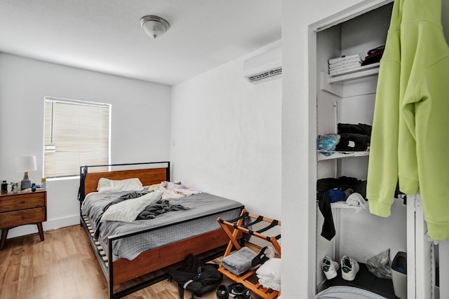 bedroom featuring a wall mounted AC and light hardwood / wood-style flooring