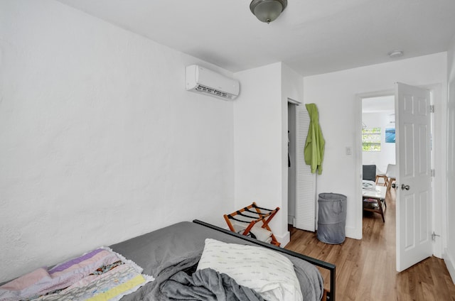 bedroom with a wall mounted air conditioner and light wood-type flooring