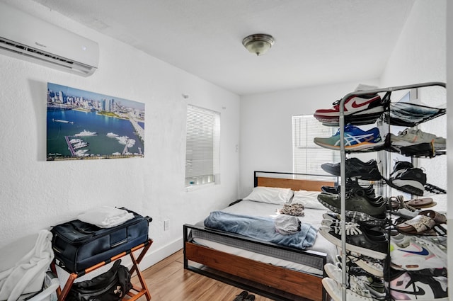 bedroom with wood-type flooring and a wall unit AC