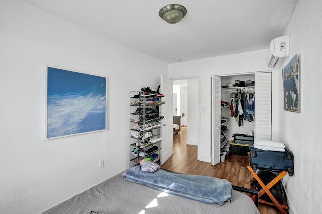 bedroom featuring hardwood / wood-style floors, a wall mounted AC, and a closet