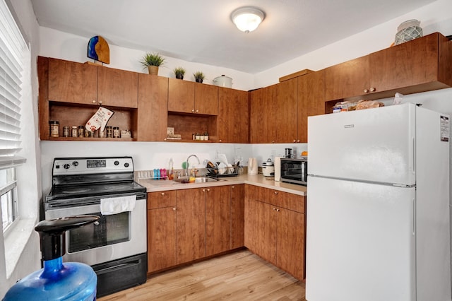 kitchen with sink, light wood-type flooring, and appliances with stainless steel finishes