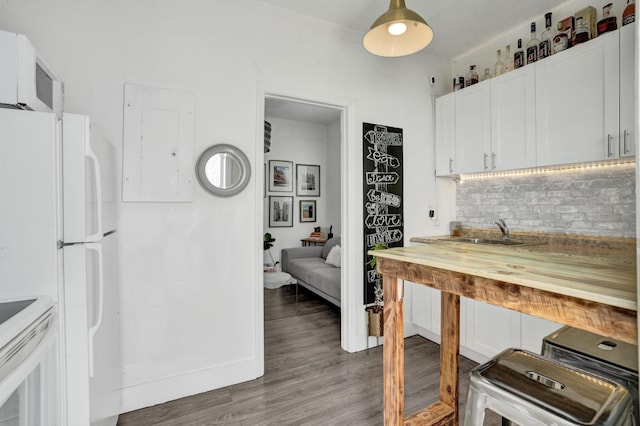 kitchen with tasteful backsplash, wood-type flooring, sink, white cabinets, and white appliances