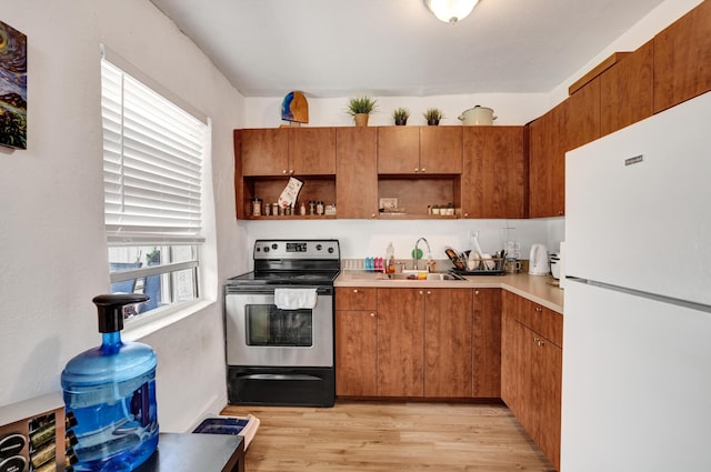 kitchen with stainless steel range with electric cooktop, sink, white fridge, and light wood-type flooring