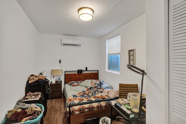 bedroom with wood-type flooring and an AC wall unit