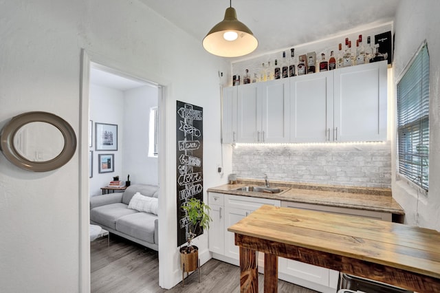 kitchen with hardwood / wood-style floors, sink, white cabinets, backsplash, and hanging light fixtures