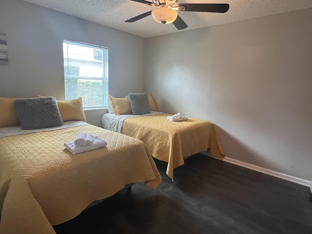 bedroom with ceiling fan, dark hardwood / wood-style floors, and a textured ceiling