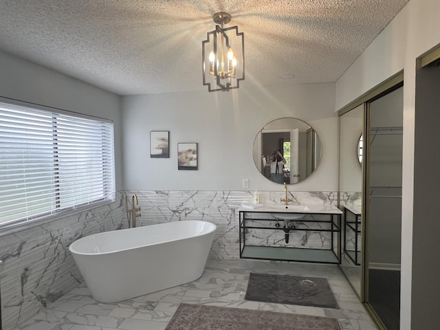 bathroom with vanity, a bath, a notable chandelier, and a textured ceiling