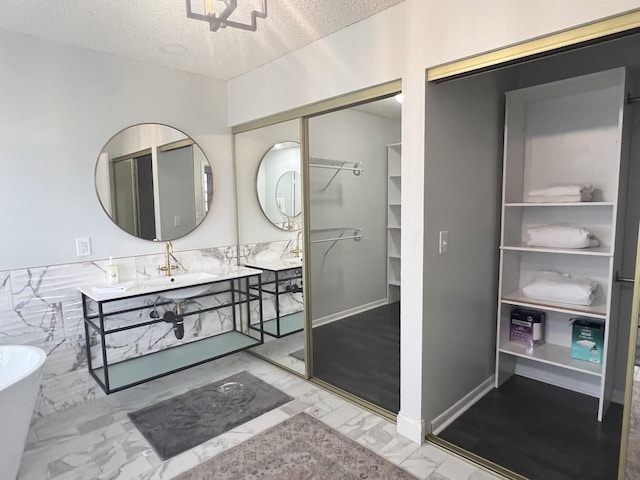 bathroom featuring a bath, sink, and a textured ceiling