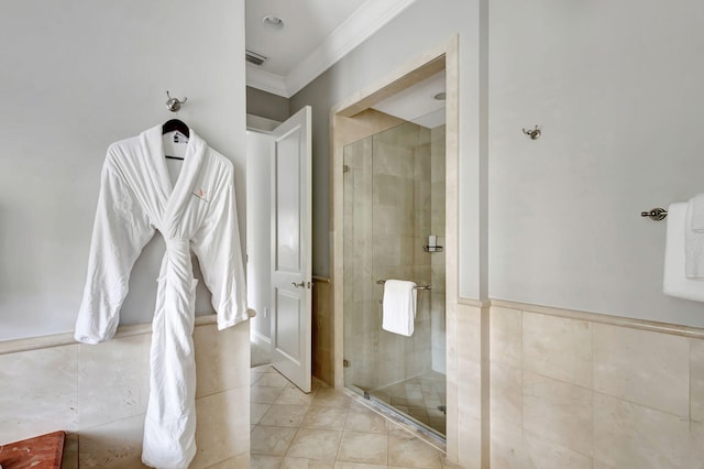 bathroom with crown molding, tile patterned floors, a shower with shower door, and tile walls