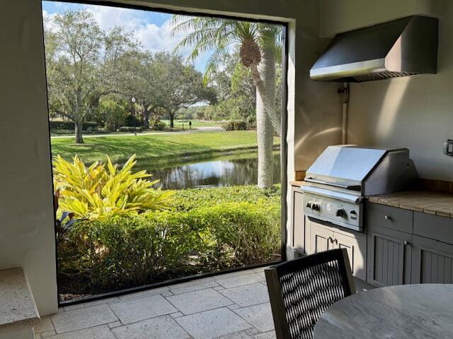 exterior space with exterior kitchen, a water view, and grilling area