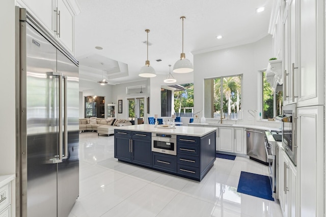 kitchen with appliances with stainless steel finishes, white cabinetry, blue cabinets, decorative light fixtures, and crown molding