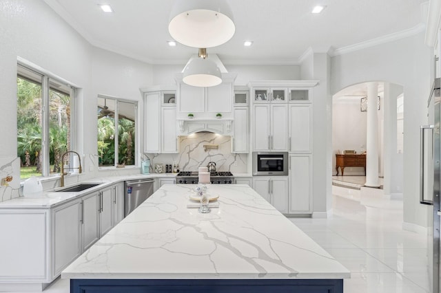 kitchen with sink, light stone counters, pendant lighting, a kitchen island, and stainless steel dishwasher