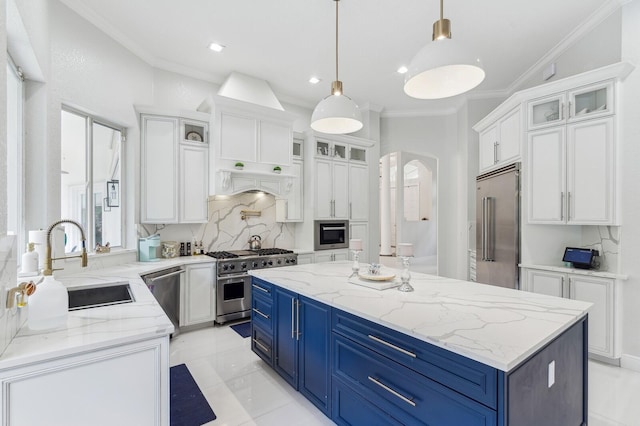 kitchen with high end appliances, blue cabinetry, white cabinets, a kitchen island, and sink