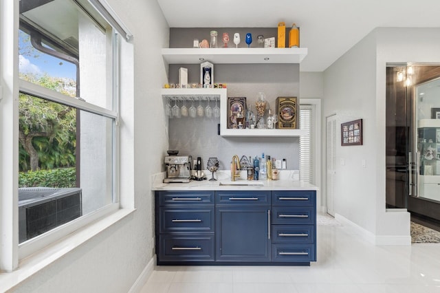 bar featuring light tile patterned flooring, blue cabinets, and sink