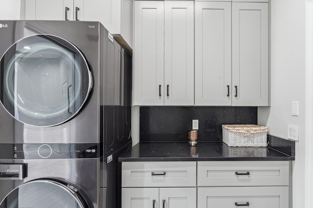 laundry room featuring stacked washing maching and dryer and cabinets