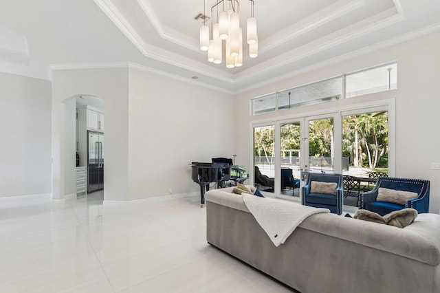 living room with french doors, ornamental molding, an inviting chandelier, and a raised ceiling