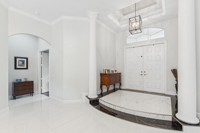 foyer entrance featuring crown molding, an inviting chandelier, a tray ceiling, and a towering ceiling