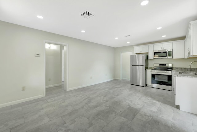 kitchen featuring stainless steel appliances, sink, white cabinets, and light stone counters