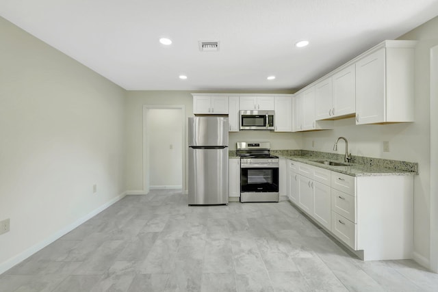 kitchen featuring light stone countertops, appliances with stainless steel finishes, sink, and white cabinets