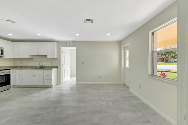 kitchen with white cabinetry, sink, light stone counters, and stainless steel appliances