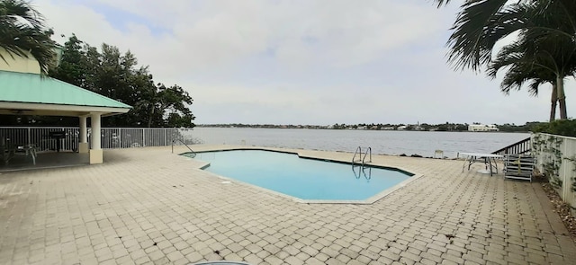 view of swimming pool featuring a water view and a patio