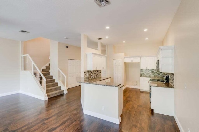 kitchen with dark hardwood / wood-style floors, dark stone countertops, white cabinets, and decorative backsplash