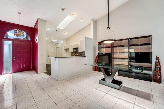 kitchen featuring decorative light fixtures, kitchen peninsula, white cabinets, and light tile patterned flooring