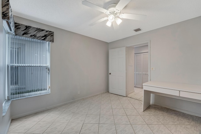 tiled spare room with a textured ceiling and ceiling fan