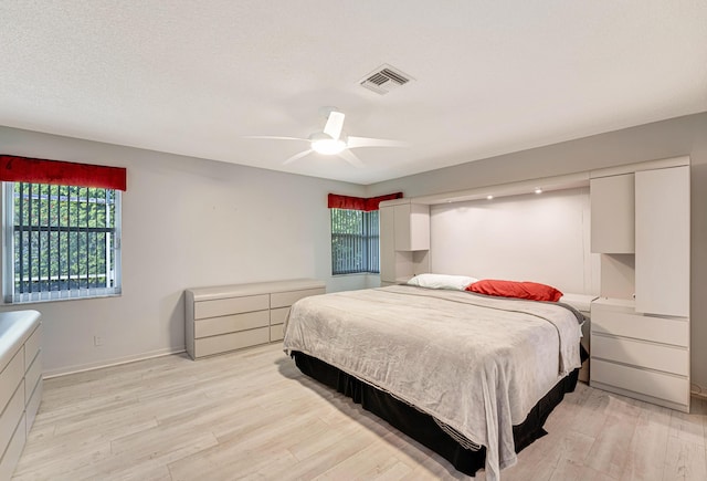 bedroom with ceiling fan, a textured ceiling, and light wood-type flooring