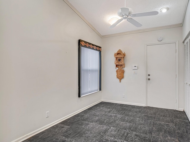 empty room featuring ceiling fan, vaulted ceiling, and a textured ceiling