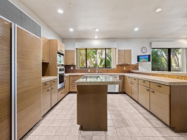 kitchen with tasteful backsplash, light tile patterned flooring, appliances with stainless steel finishes, and kitchen peninsula