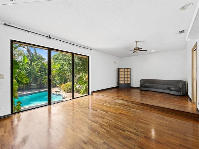 interior space featuring ceiling fan, wood-type flooring, and a textured ceiling