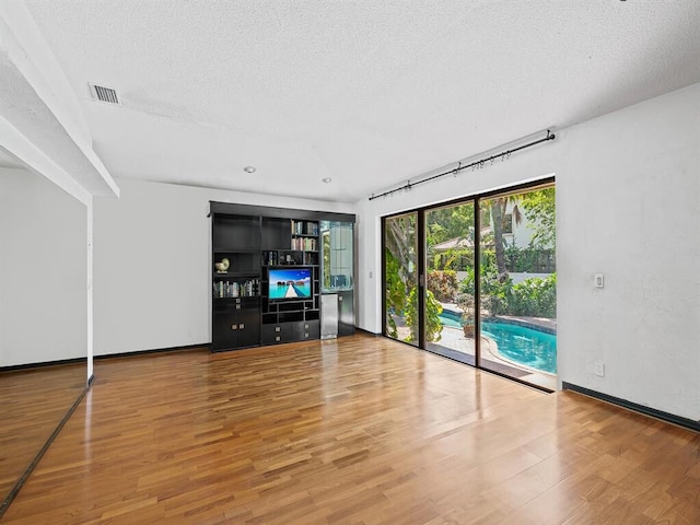 unfurnished living room featuring hardwood / wood-style flooring and a textured ceiling