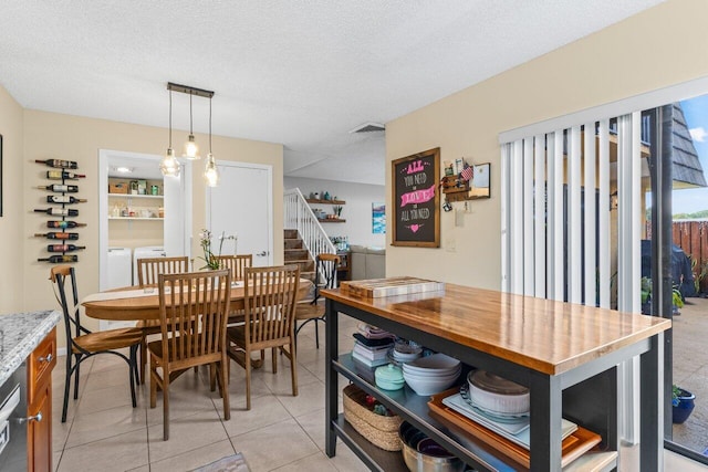 dining space featuring light tile patterned floors, washing machine and dryer, and a textured ceiling