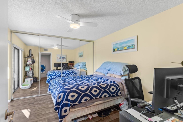 bedroom with wood-type flooring, ceiling fan, a textured ceiling, and a closet