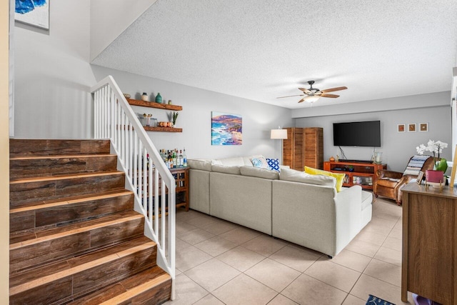 living room featuring ceiling fan, a textured ceiling, and light tile patterned floors