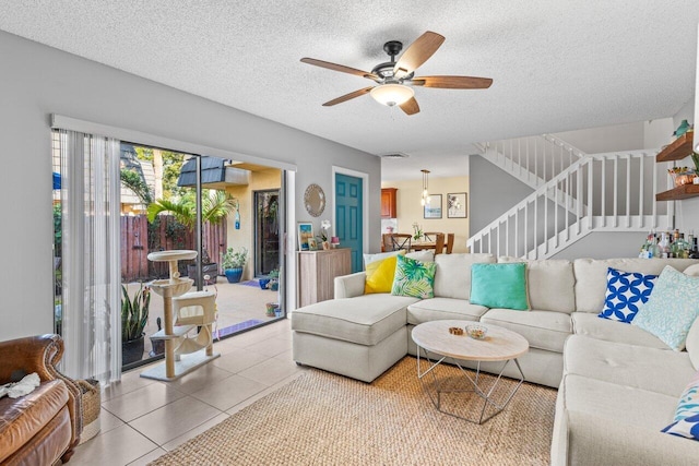 living room featuring ceiling fan, tile patterned floors, and a textured ceiling