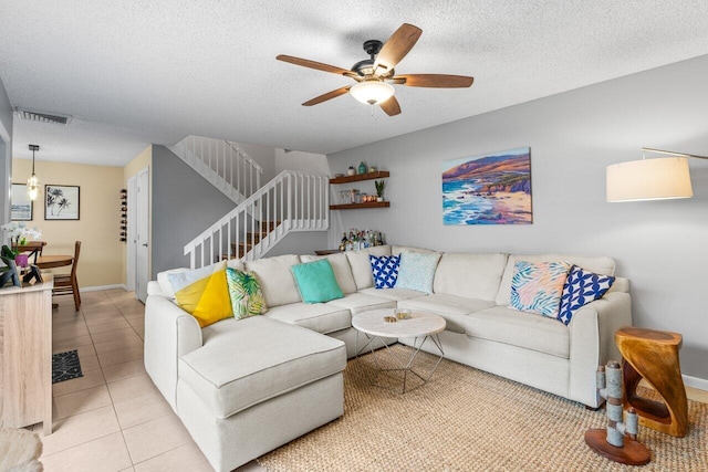 tiled living room with ceiling fan and a textured ceiling