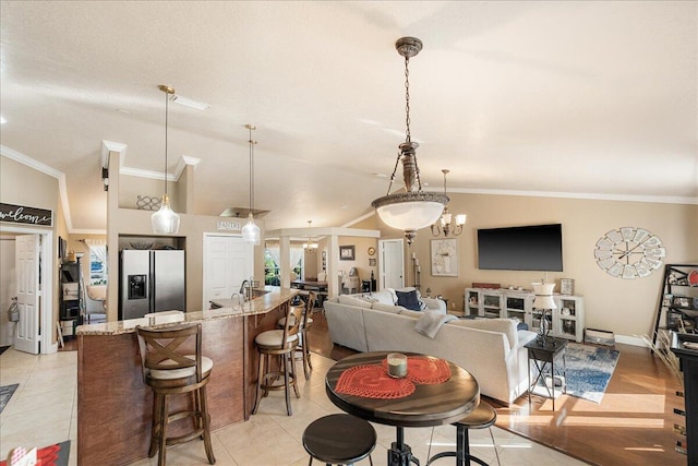 living room featuring vaulted ceiling, sink, ornamental molding, and light tile patterned flooring