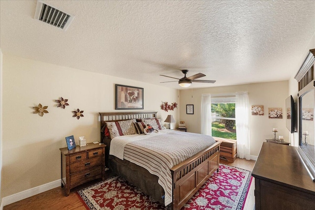 bedroom with ceiling fan, a textured ceiling, and light hardwood / wood-style floors