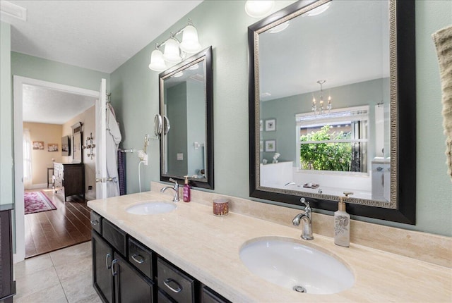 bathroom with vanity, a bathtub, tile patterned floors, and a chandelier