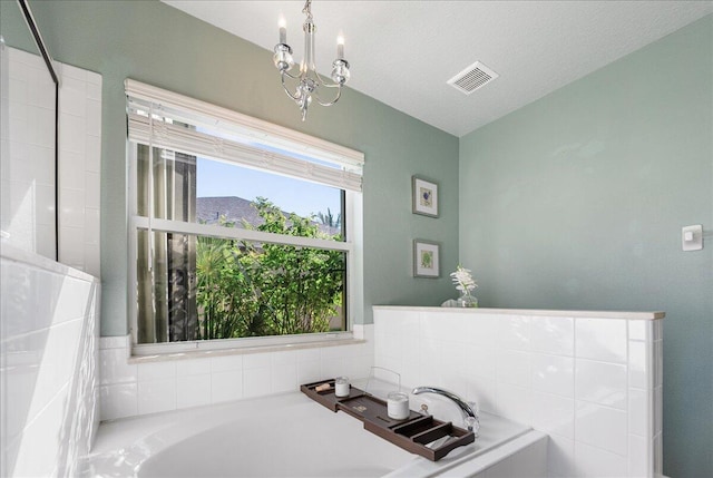 bathroom with a washtub, a textured ceiling, and a chandelier