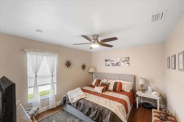 bedroom featuring ceiling fan, hardwood / wood-style floors, and a textured ceiling