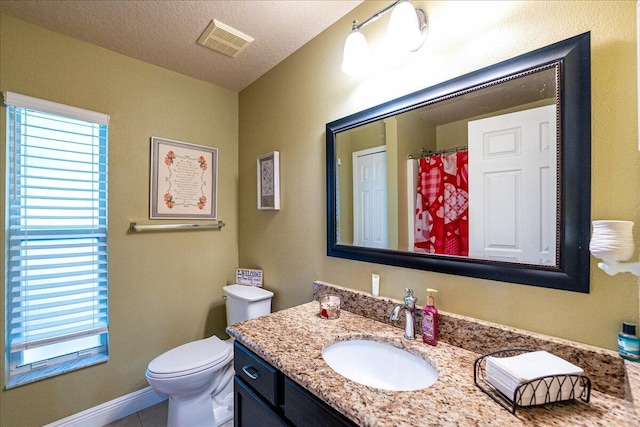 bathroom with a healthy amount of sunlight, vanity, toilet, and a textured ceiling